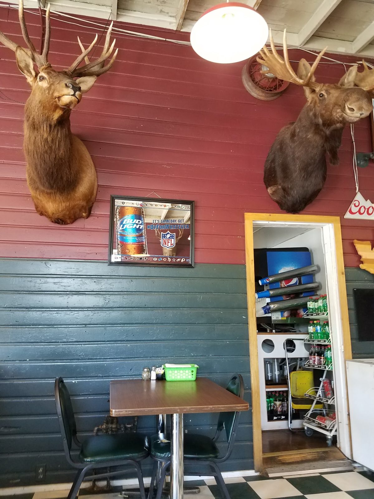 Inside Cabin City Q: elk and moose mounts over the red and green walls, with the dining tables below